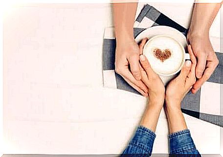 The hands of a couple around a cup of coffee. 