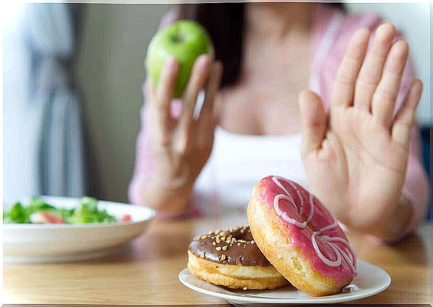 A woman who eats an apple and says no to sweets. 